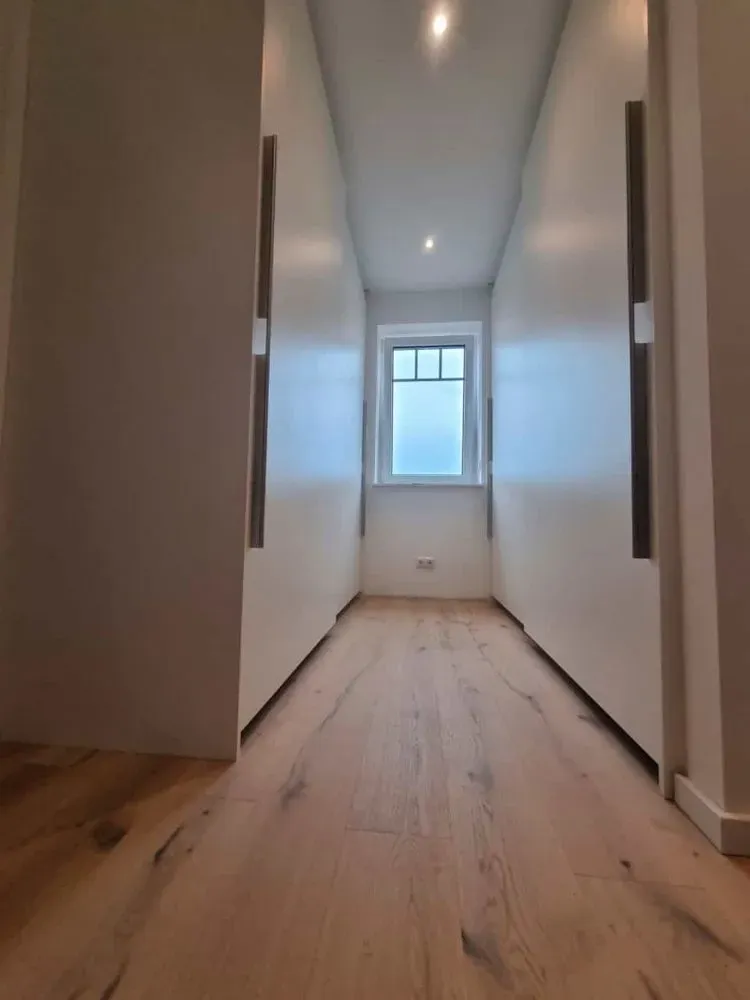 Ein langer Flur mit Holzboden und weißen Wänden