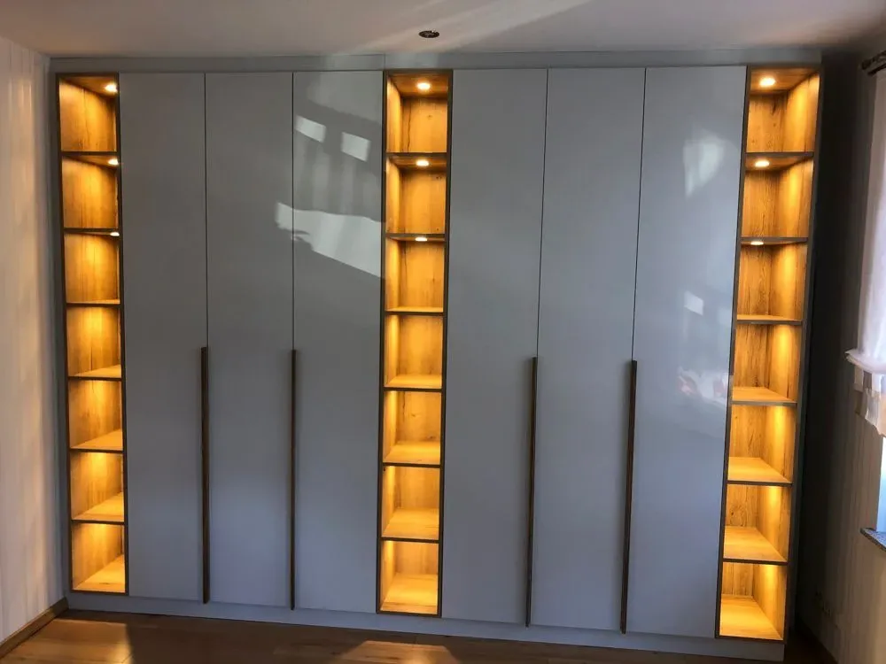 Ein großer Kleiderschrank mit vielen Regalen und Lichtern in einem Zimmer.