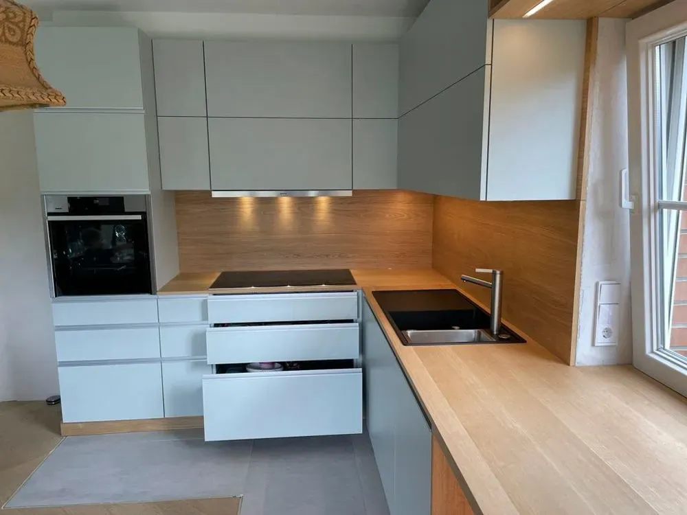 Eine Küche mit weißen Schränken und Holzarbeitsplatten