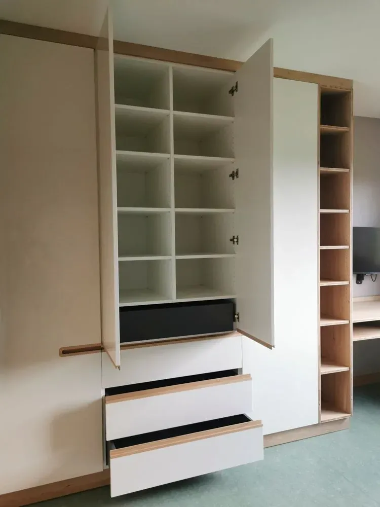 Ein Kleiderschrank mit Schubladen und Regalen in einem Zimmer