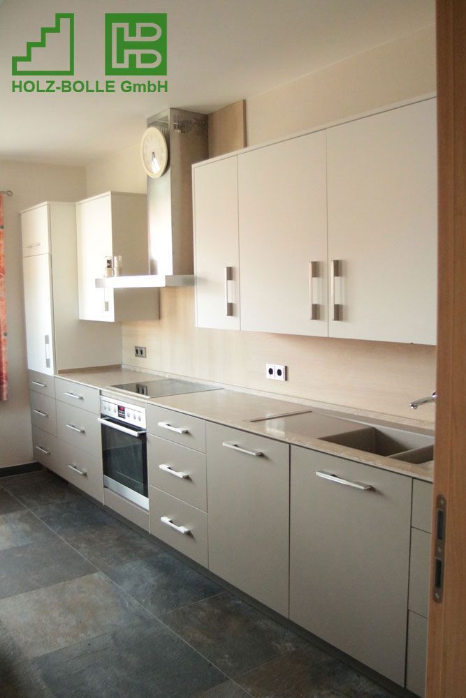 Eine Küche mit weißen Schränken und einem Schild mit der Aufschrift „Holz-Bolle GmbH“