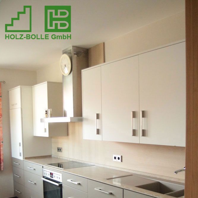 Eine Küche mit weißen Schränken und einem Schild mit der Aufschrift „Holz-Bolle GmbH“