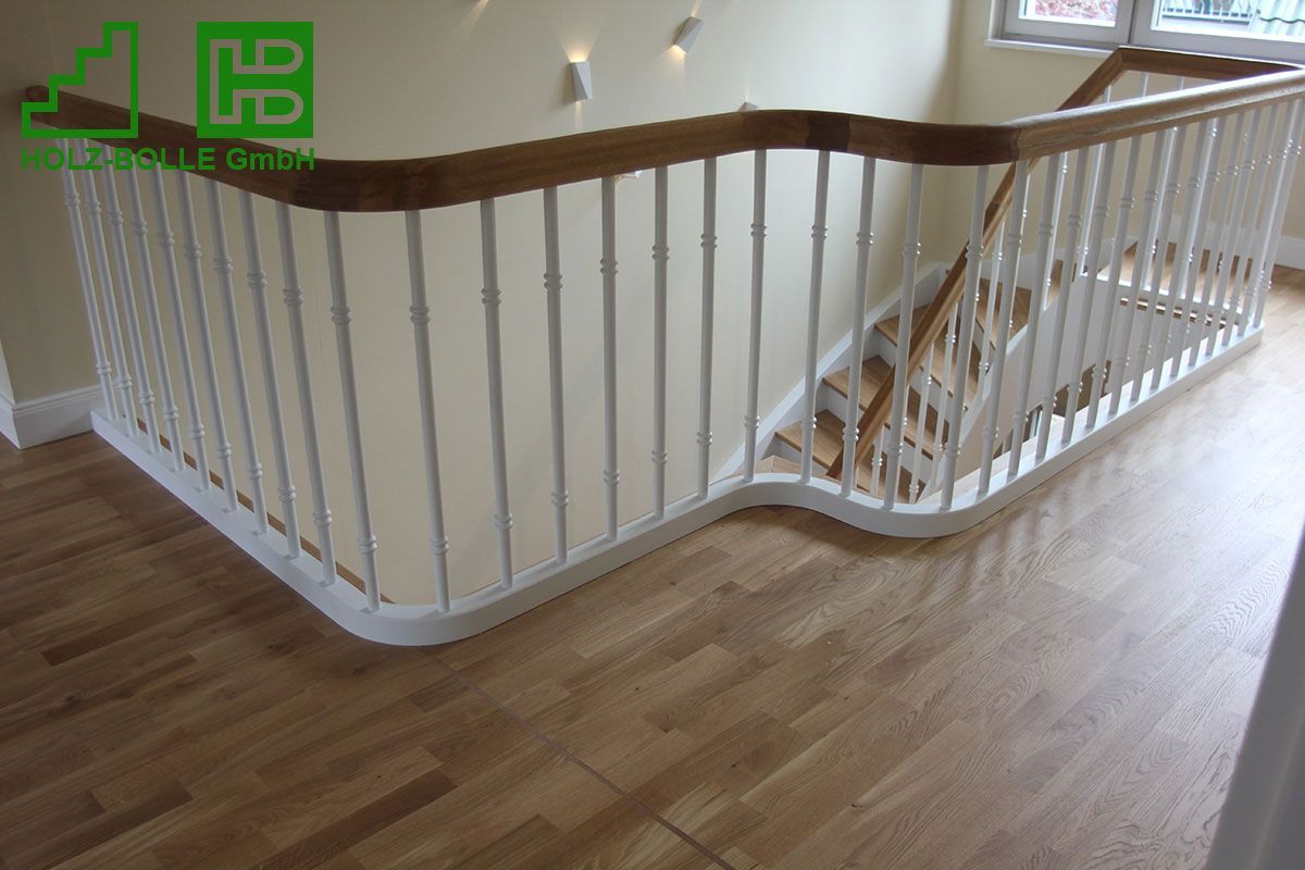 Eine Holztreppe mit weißem Geländer und Holzhandlauf.