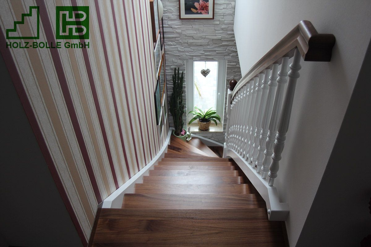 Eine Holztreppe mit weißem Geländer und gestreifter Wand