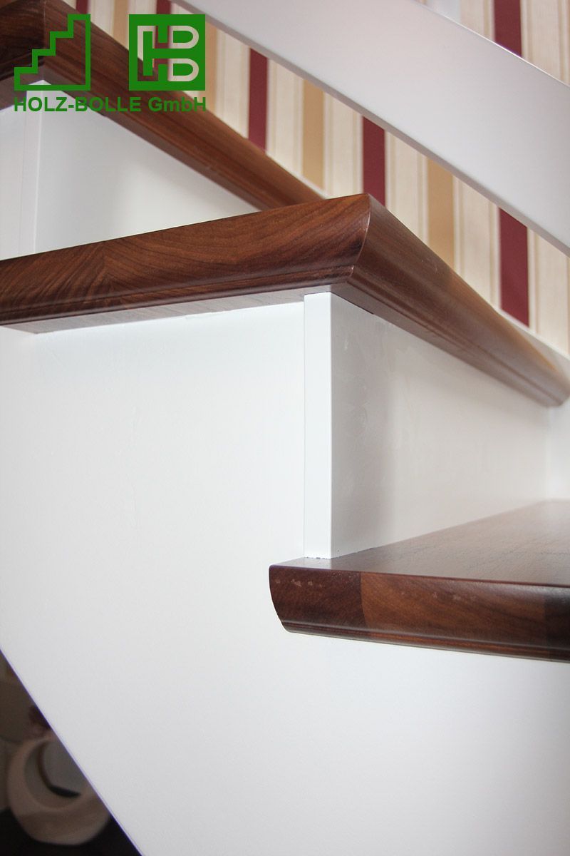 Eine Treppe mit Holzgeländer und weißer Wand