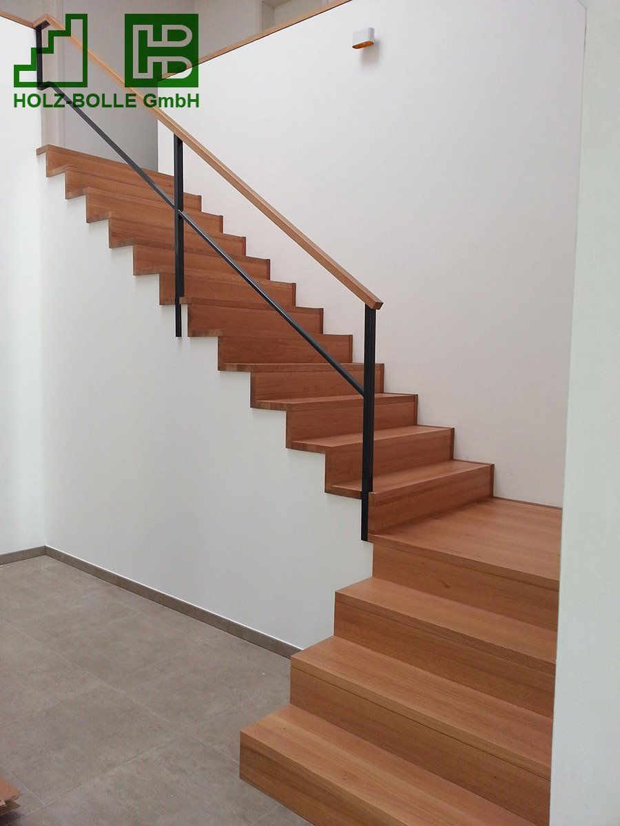 Eine Holztreppe mit Metallgeländer und einem hb-Logo an der Wand