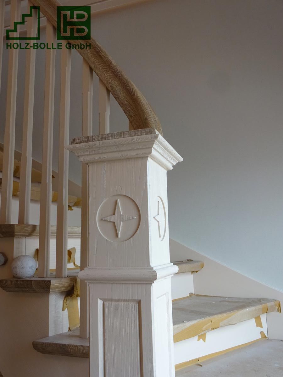 Eine Treppe mit einem Holzgeländer und einem weißen Pfosten mit einem Stern darauf.