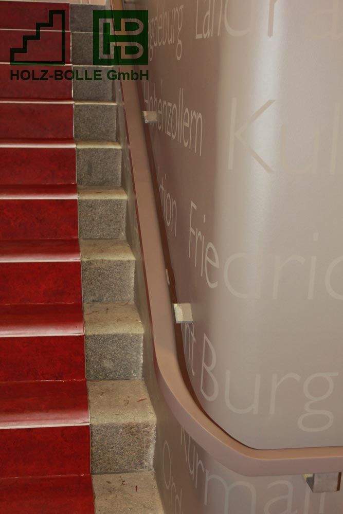 Eine Treppe mit einem roten Teppich und einer Wand mit der Aufschrift „Holz Bolle GmbH“