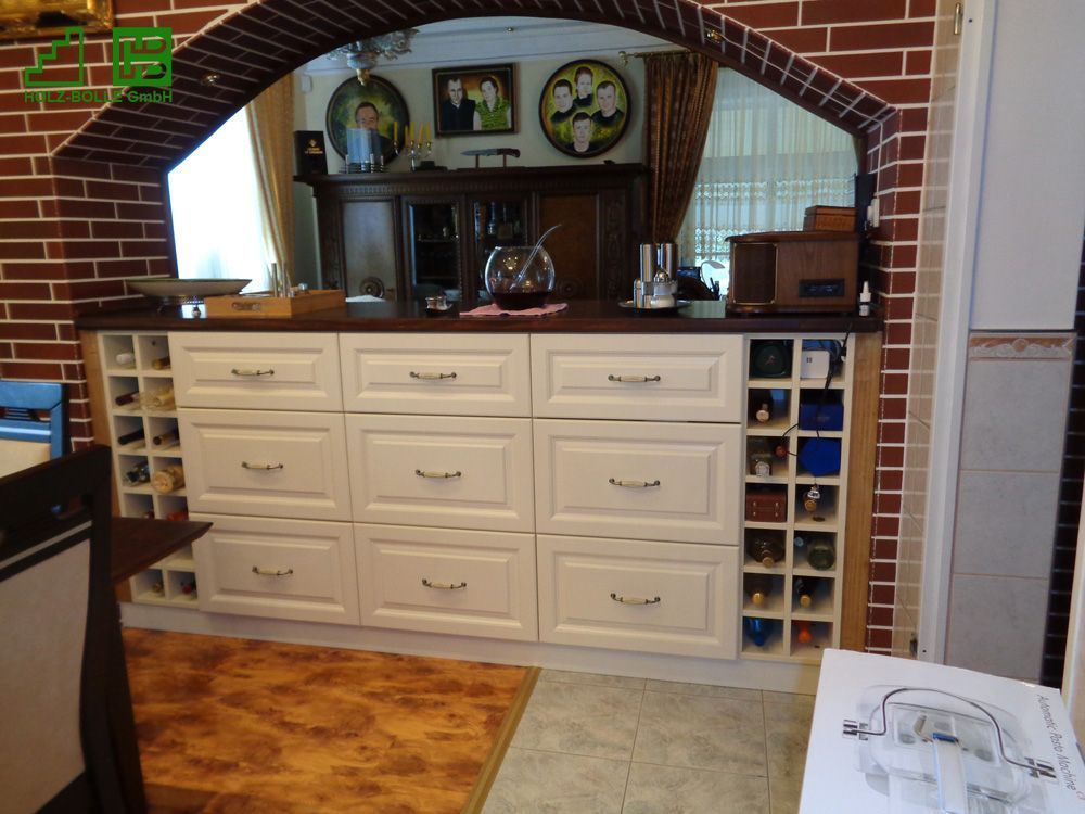 Eine Küche mit weißen Schränken und einem Weinregal