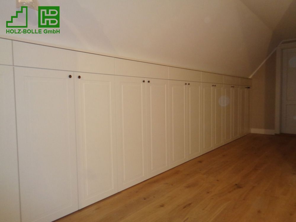 Ein Raum mit Holzboden und weißen Schränken an der Wand.