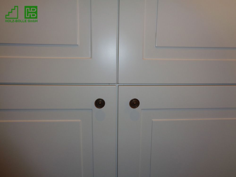 Eine Nahaufnahme von einem weißen Schrank mit Holzknöpfen