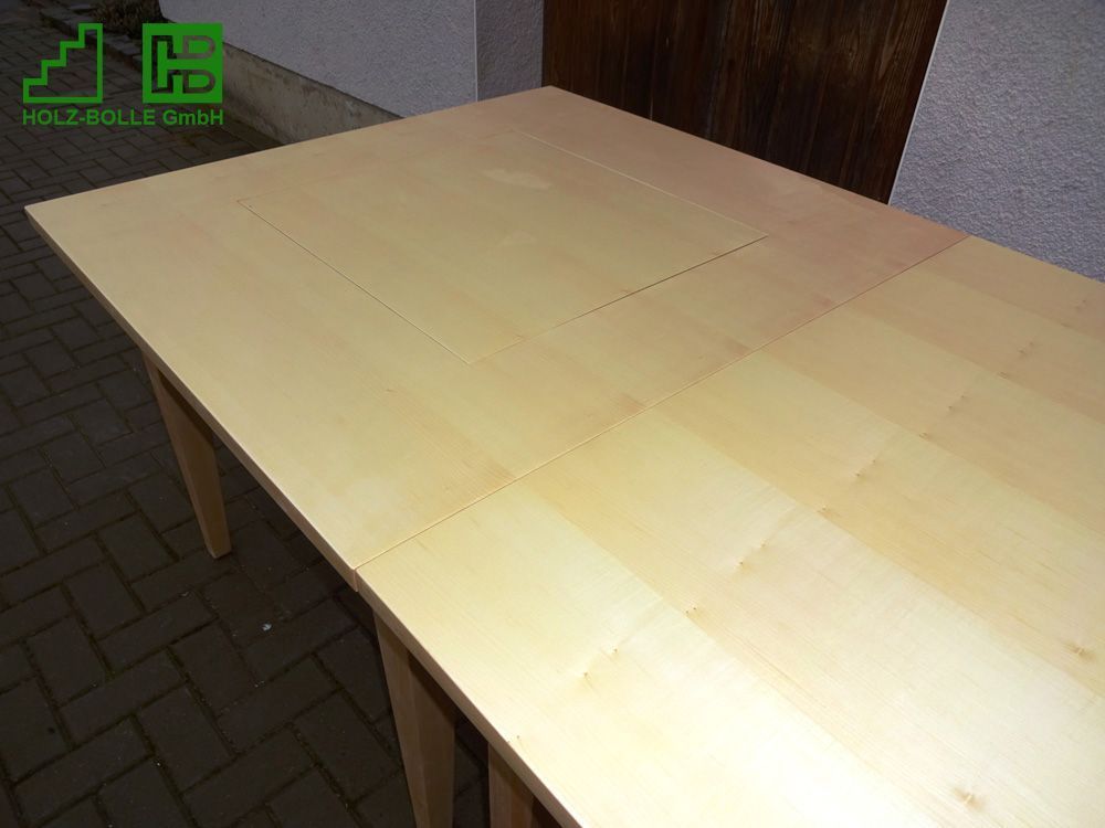 Auf einem gepflasterten Gehweg steht ein Holztisch.