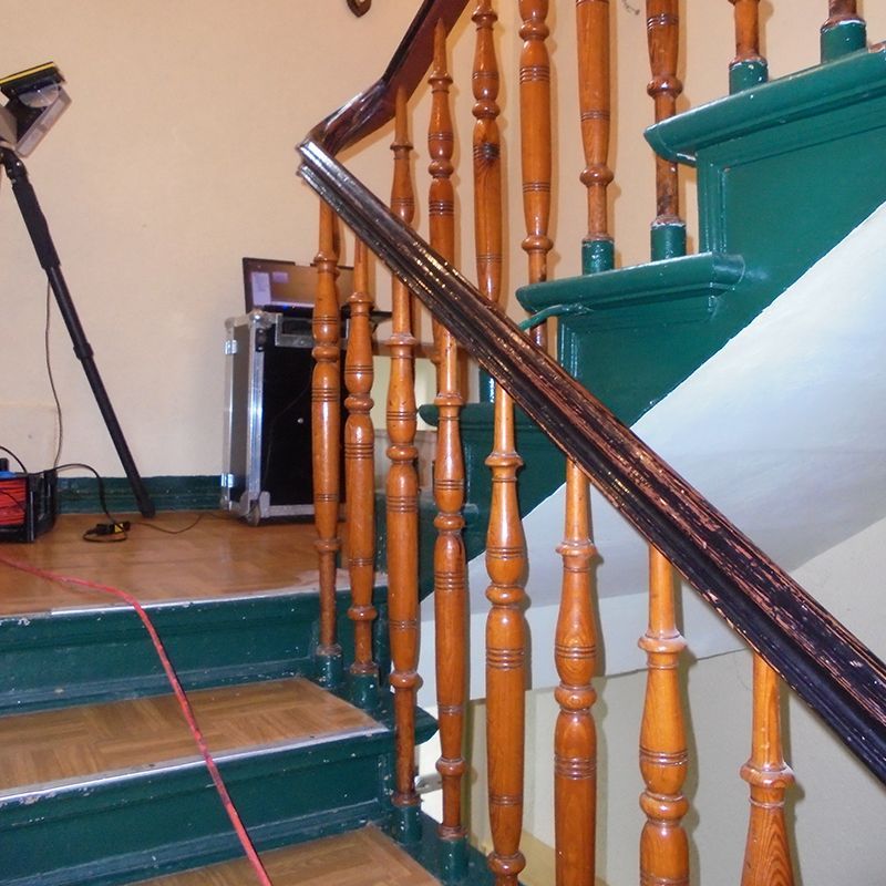 Eine Treppe mit Holzgeländer und grünen Stufen