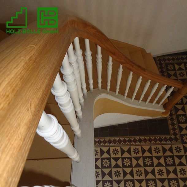 Eine Holztreppe mit weißem Geländer und Fliesenboden