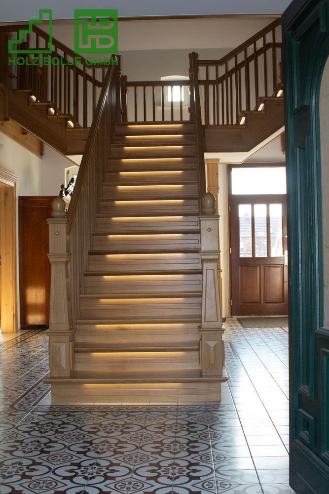 Eine Holztreppe mit Lichtern auf den Stufen in einem Flur.