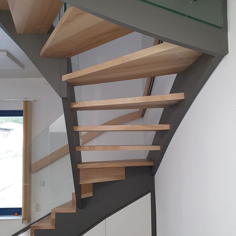 Eine Wendeltreppe mit Holzstufen und Glasgeländer