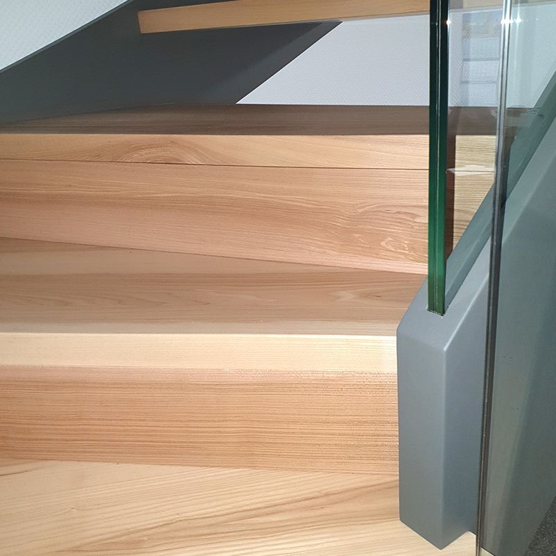 Eine Nahaufnahme einer Holztreppe mit einem Glasgeländer