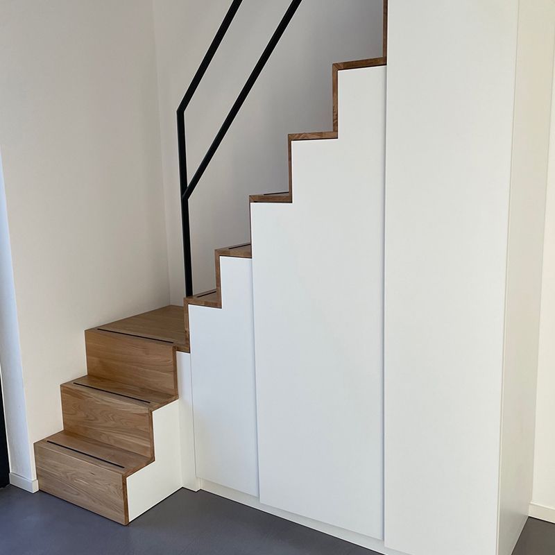 Die treppe ist aus holz und weiß und hat ein schwarzes geländer.