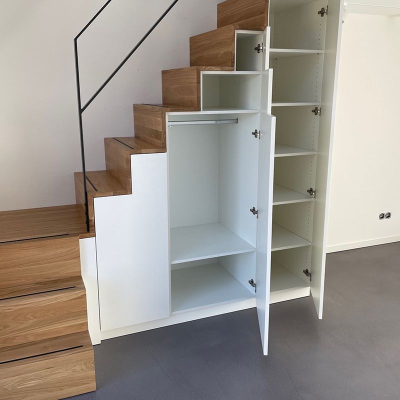 Eine Holztreppe mit einem weißen Schrank darunter