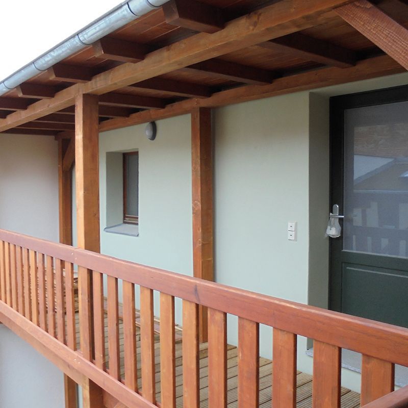 Ein Balkon mit einem Holzgeländer, das zu einer Tür führt