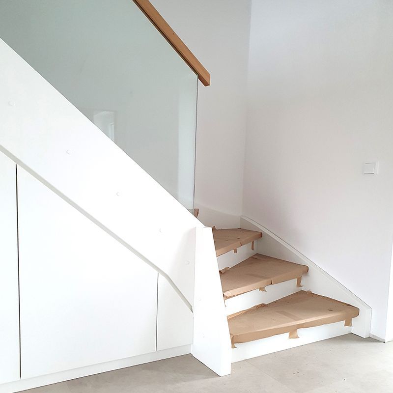 Eine weiße Treppe mit Holzstufen und einem Glasgeländer