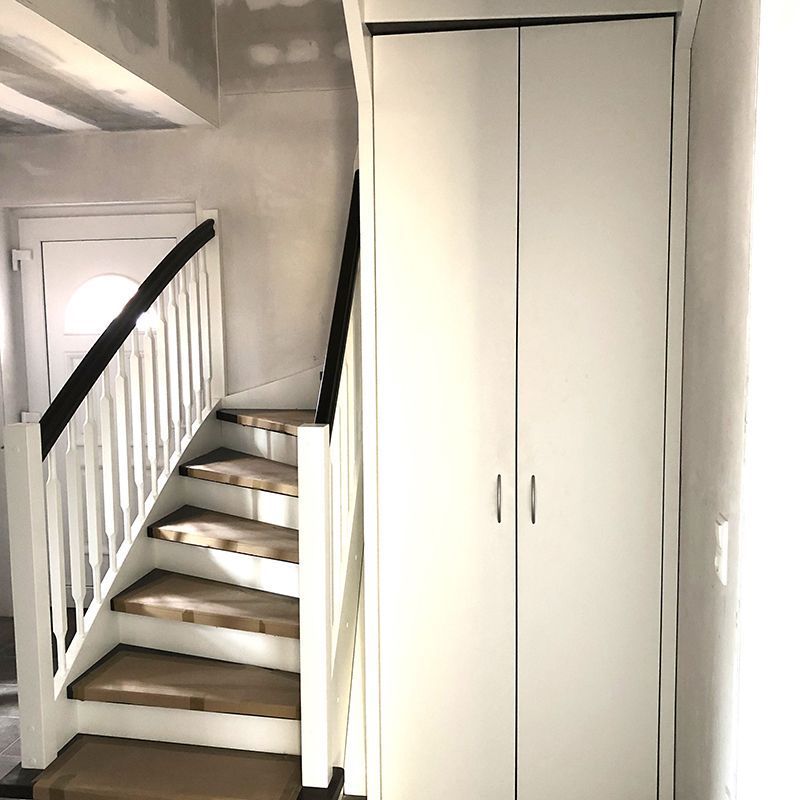 Eine weiße Treppe mit Holzstufen steht neben einem weißen Schrank.