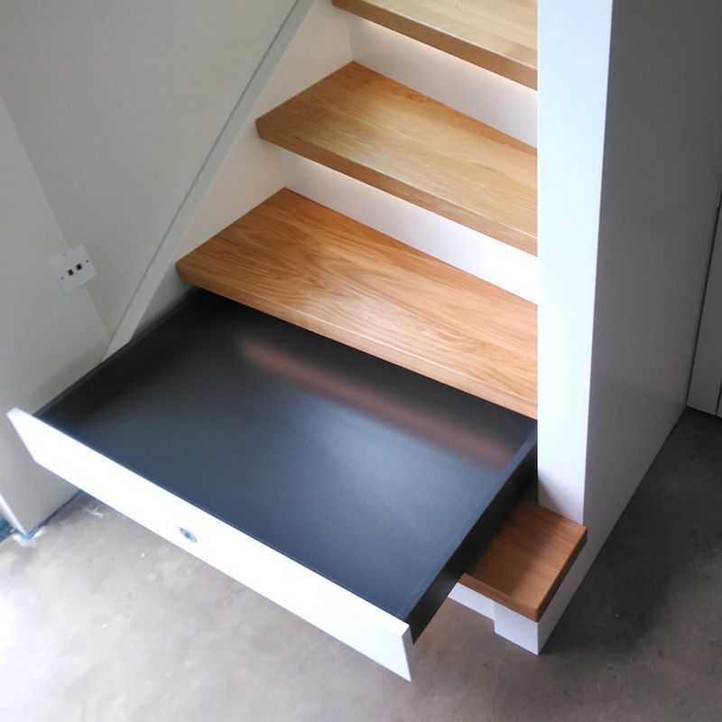 Eine Holztreppe mit einer schwarzen Schublade darunter