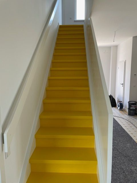 Eine gelbe Treppe mit weißem Geländer
