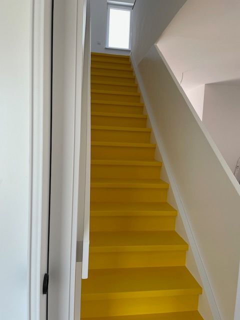 Die Treppe ist gelb gestrichen und das Geländer ist weiß.