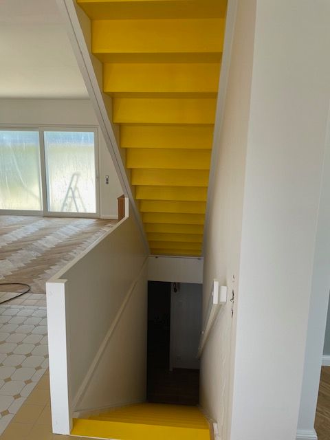 Eine gelbe Treppe in einem Haus mit einem weißen Geländer