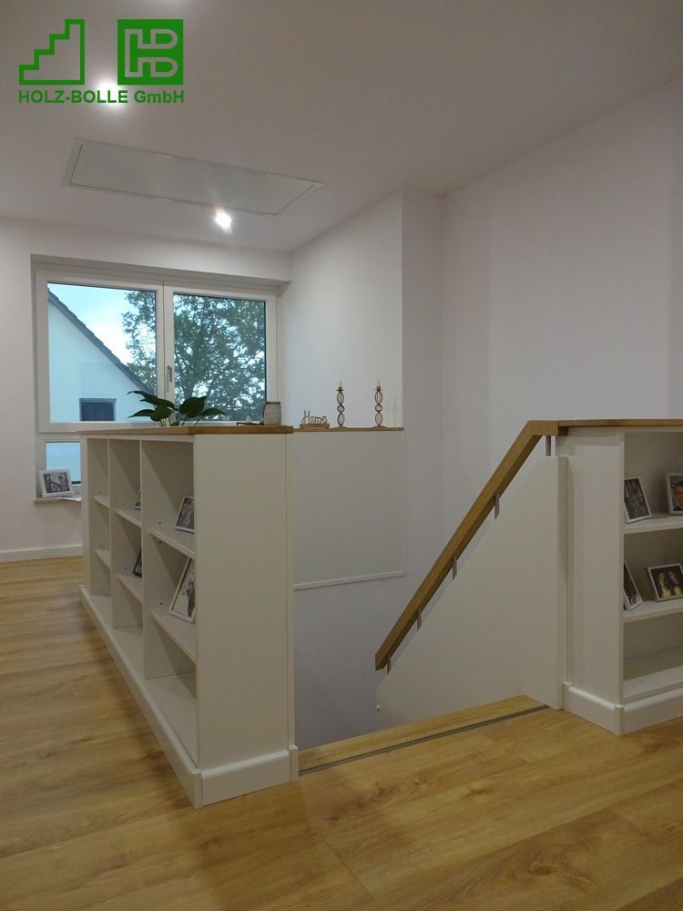 Eine Treppe mit Holzgeländer und Regalen in einem Raum.