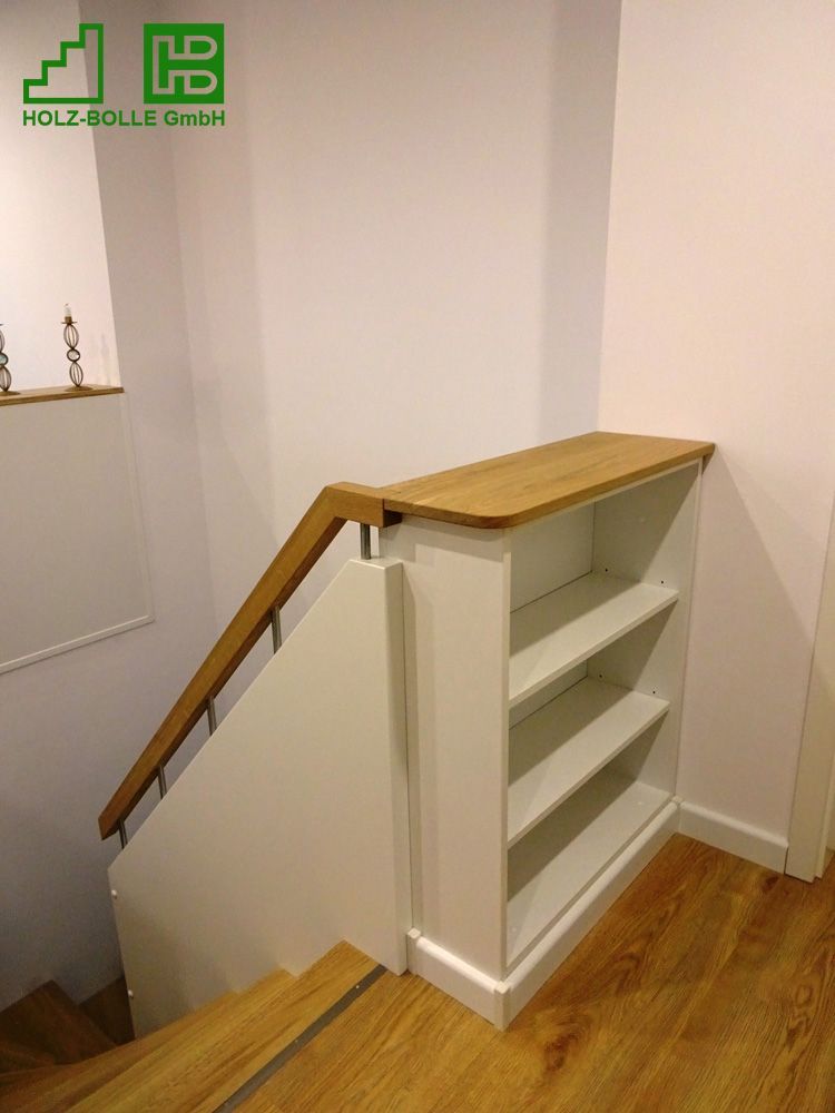 Eine Treppe mit einem Bücherregal darunter und einem Holzgeländer.