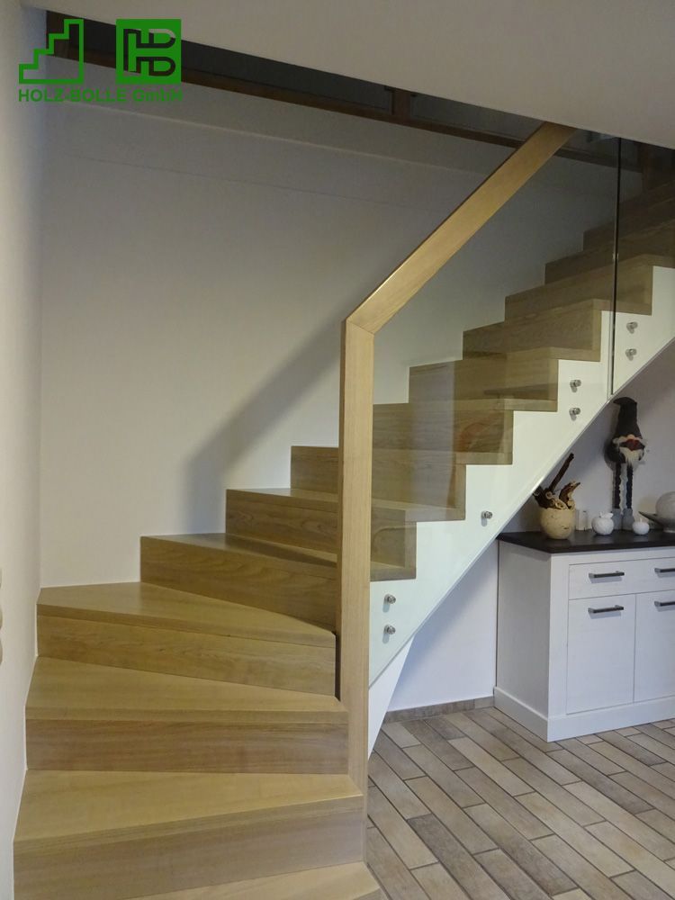 Eine Holztreppe mit Glasgeländer in einem Wohnzimmer