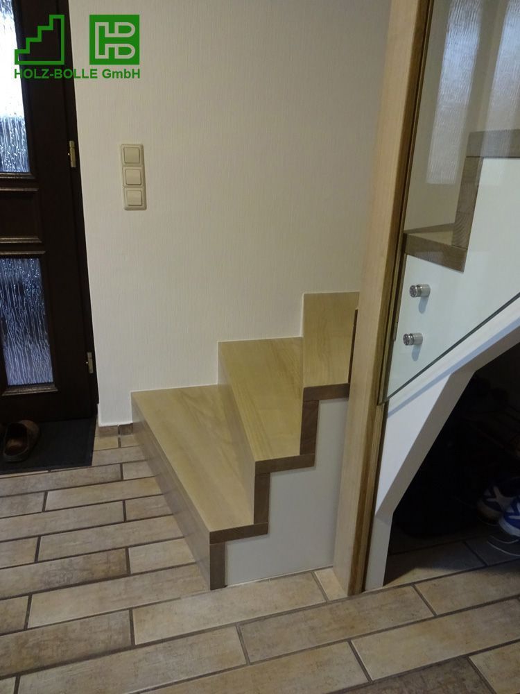 Eine Holztreppe mit einem Glasgeländer in einem Flur