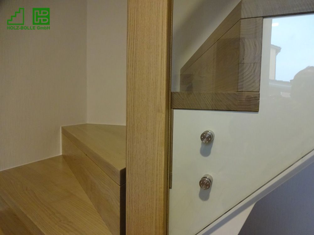 Eine Nahaufnahme einer Holztreppe mit einem Glasgeländer.