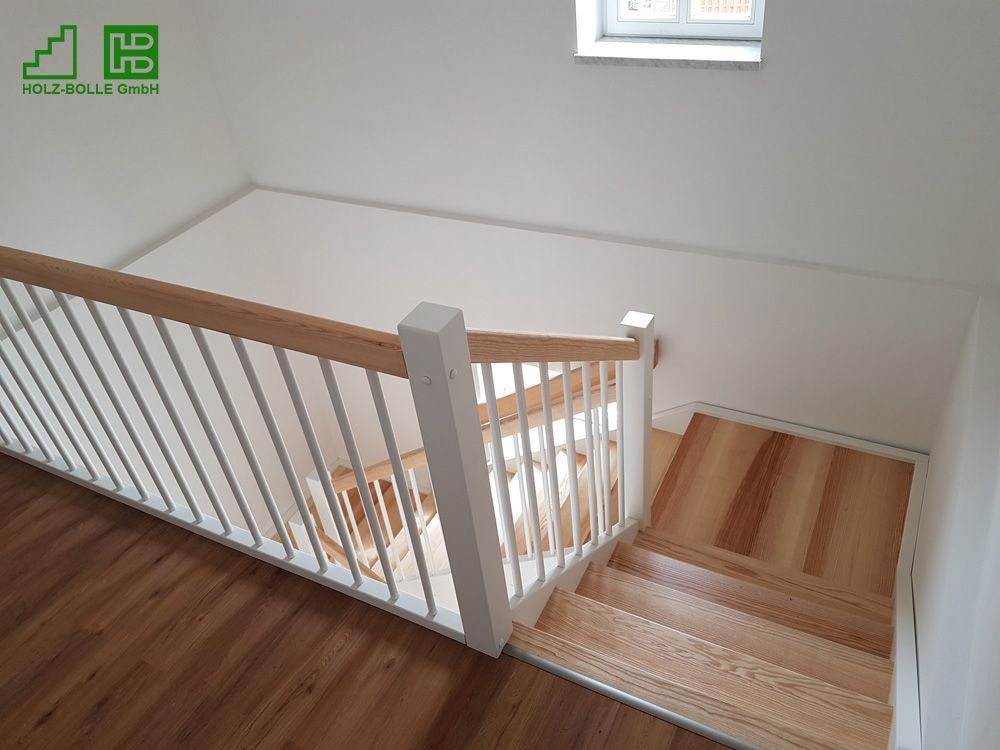 Eine Holztreppe mit weißem Geländer und Holzstufen in einem Raum.