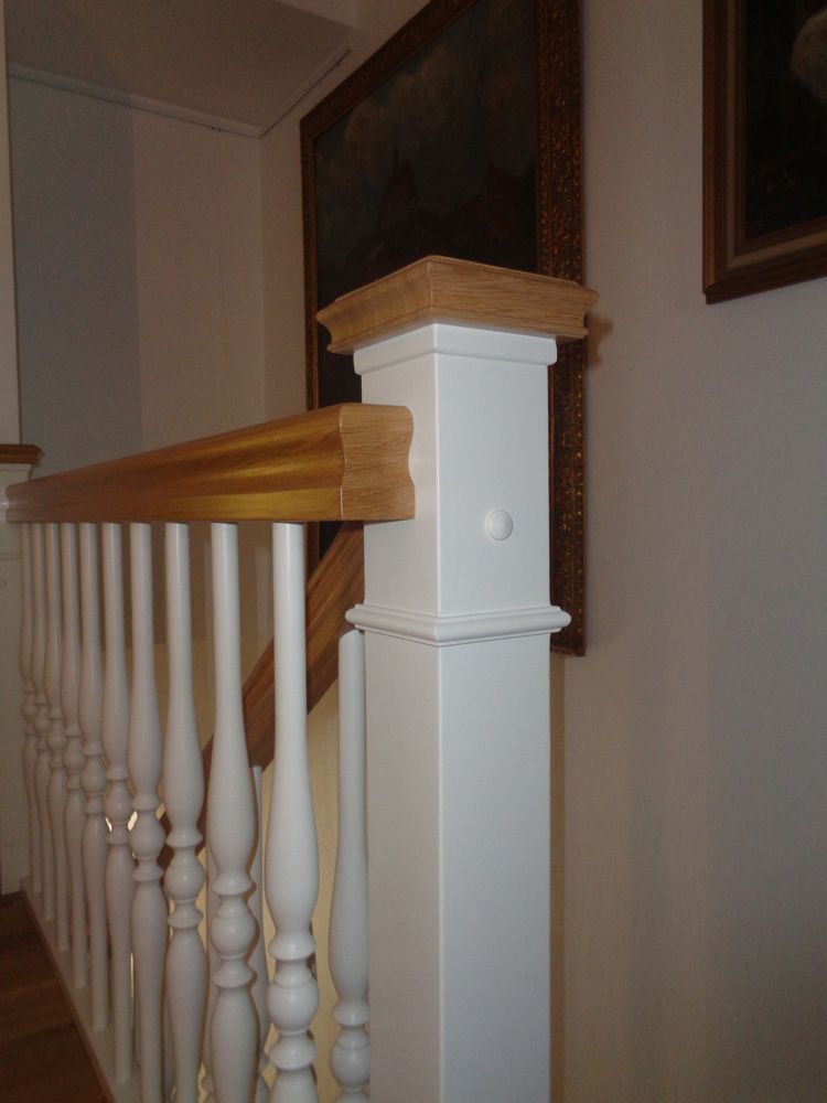 Ein weißes Geländer mit einem Holzhandlauf an einer Treppe.