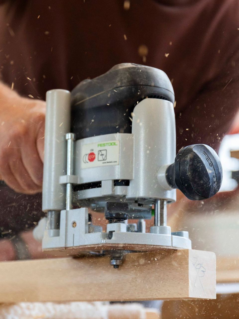 Eine Person verwendet eine Oberfräse, um ein Stück Holz zu schneiden.