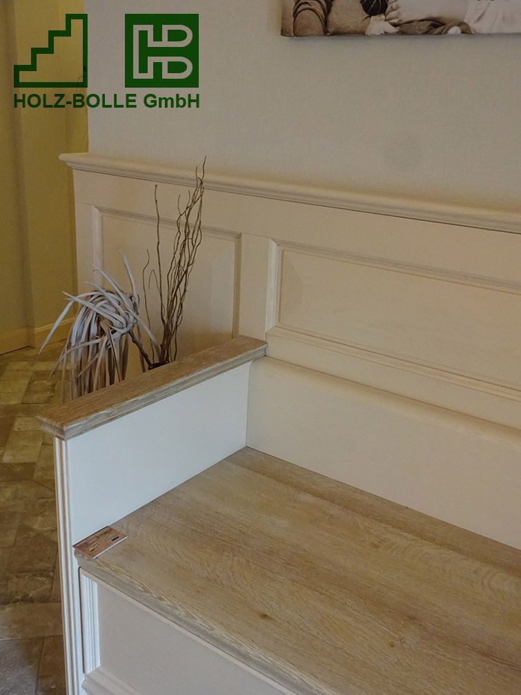 Eine Holzbank mit einer Blumenvase darauf in einem Raum.