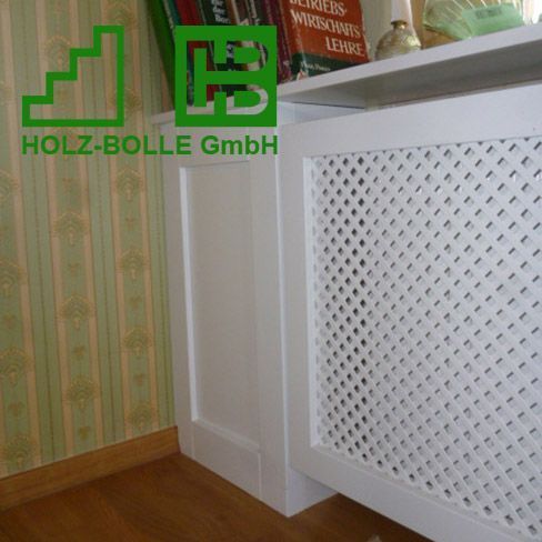 Eine weiße Heizkörperabdeckung liegt auf einem Holzboden neben einem Bücherregal.