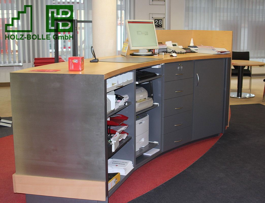 Ein Schreibtisch mit einem Computer und einem Schild mit der Aufschrift „Holz-Bölle GmbH“