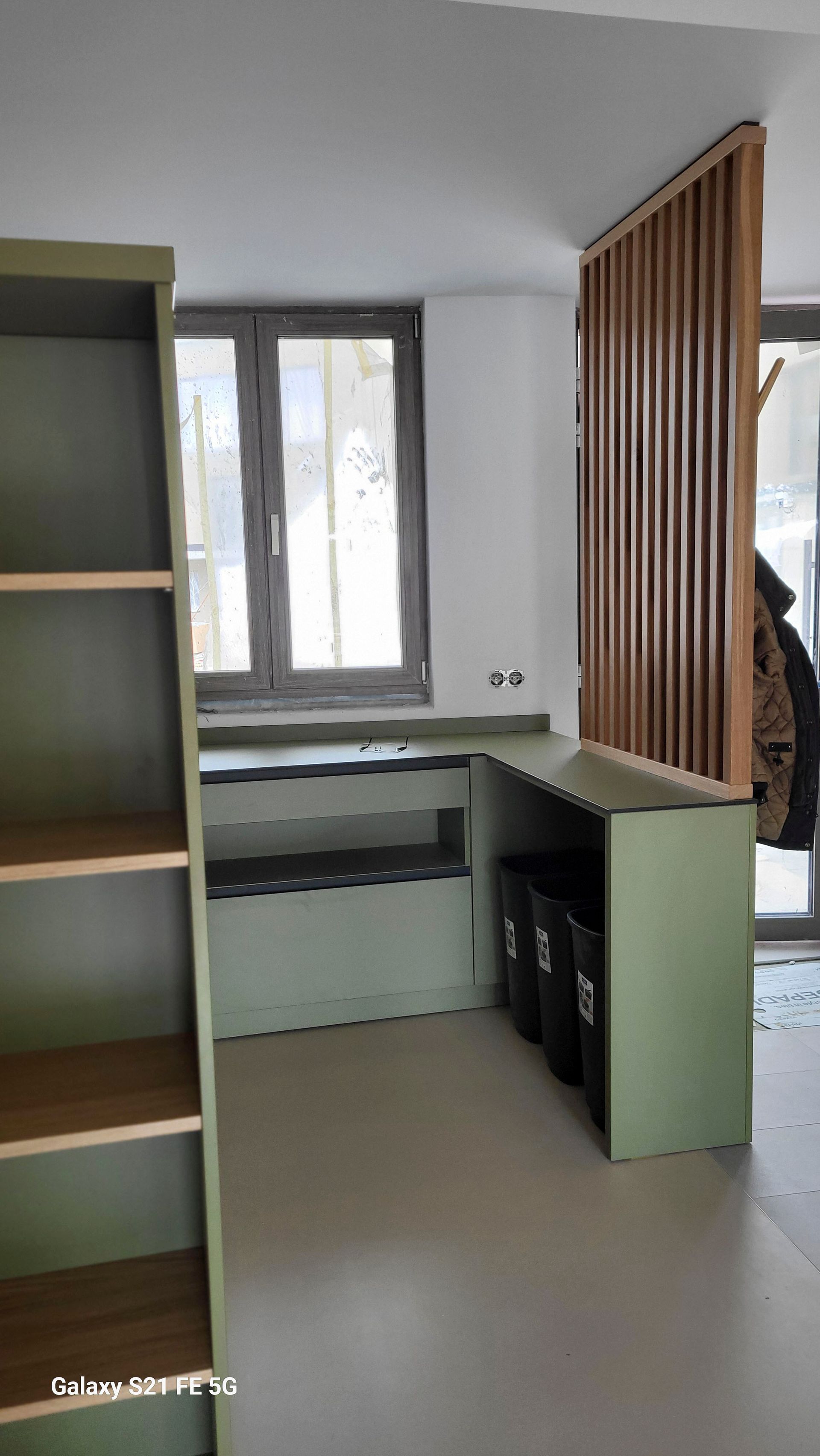 Ein Zimmer mit einem Schreibtisch, Regalen und einem Fenster.