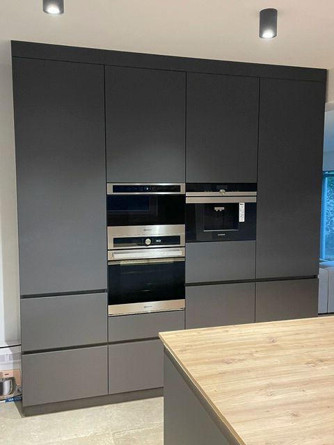 Eine Küche mit schwarzen Schränken und Geräten aus Edelstahl