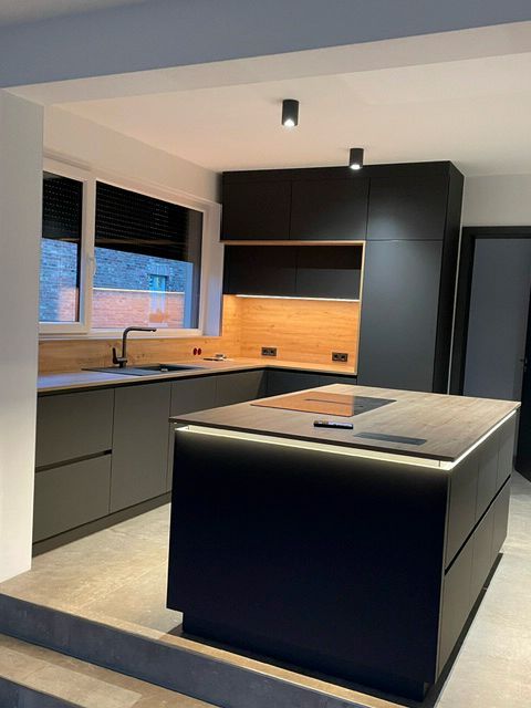 Eine Küche mit schwarzen Schränken und einer großen Insel in der Mitte