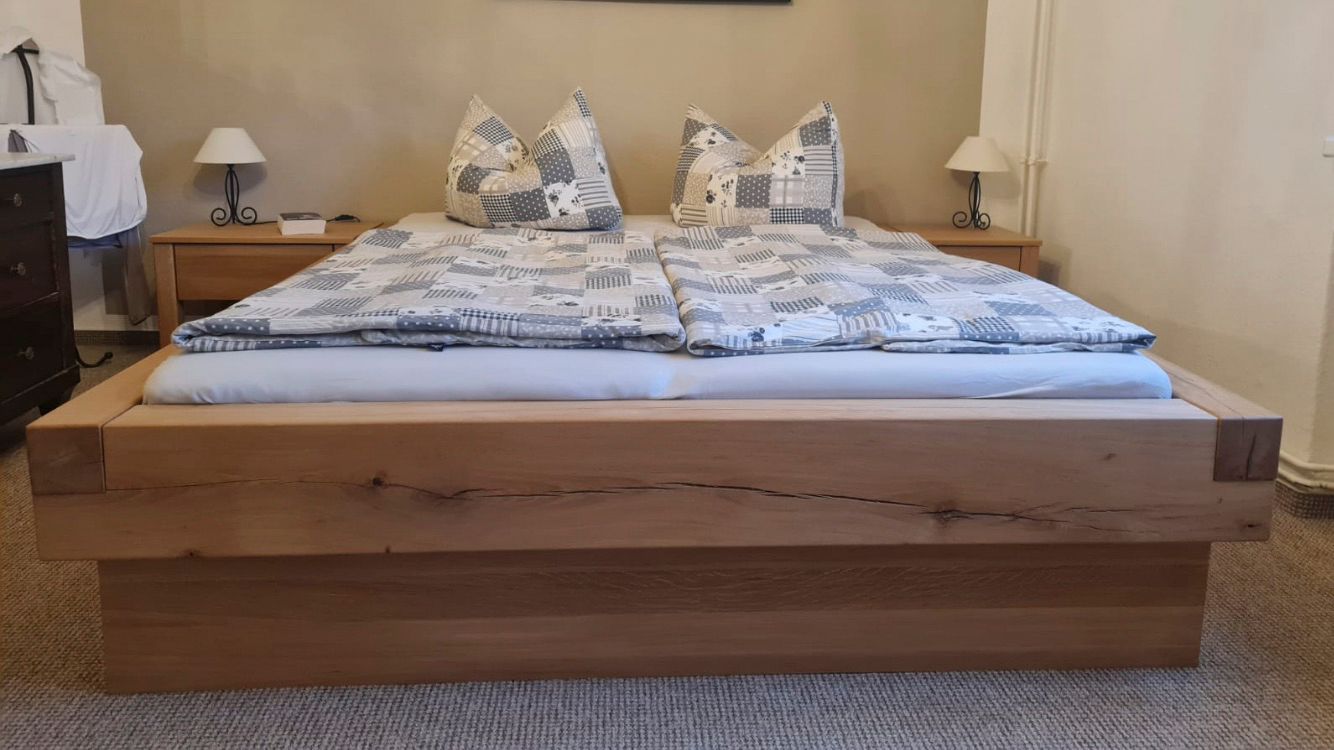 Ein Holzbett mit Matratze und Kissen in einem Schlafzimmer.