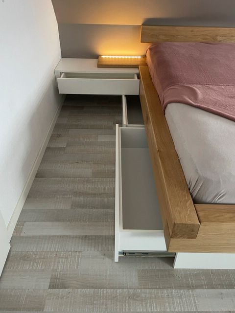 Ein Bett mit einer Schublade darunter in einem Schlafzimmer.