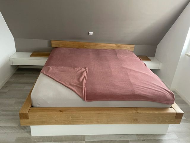 Ein Bett mit einer rosa Decke darauf in einem Schlafzimmer.