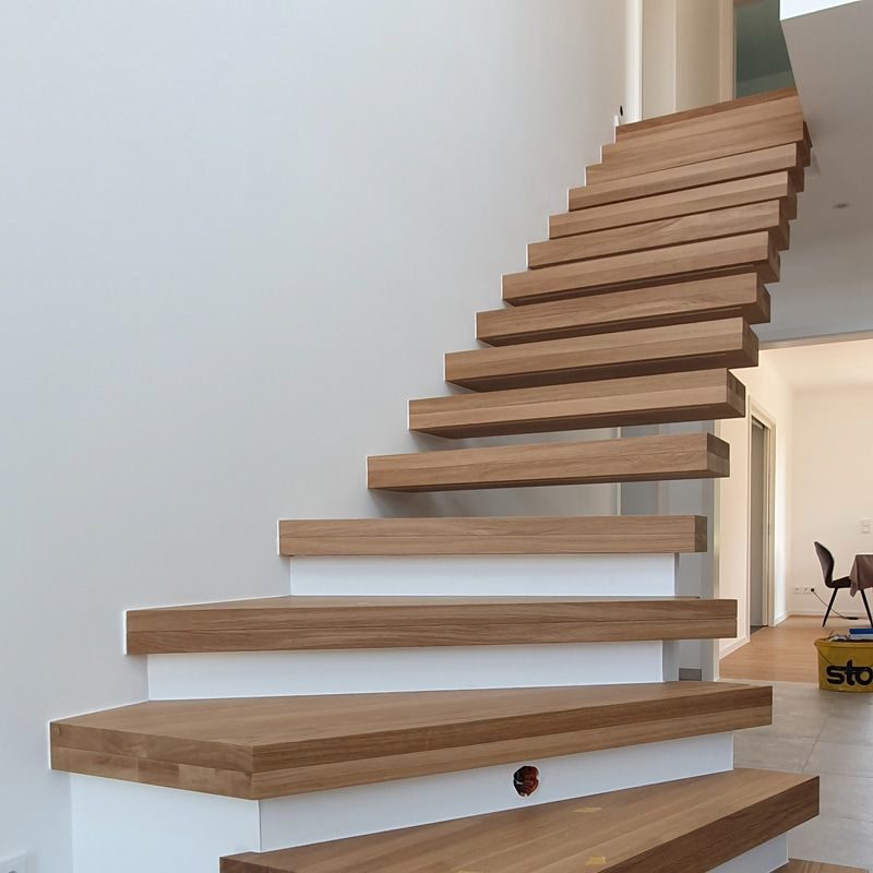 Eine Holztreppe mit weißen Stufen hinauf in den zweiten Stock