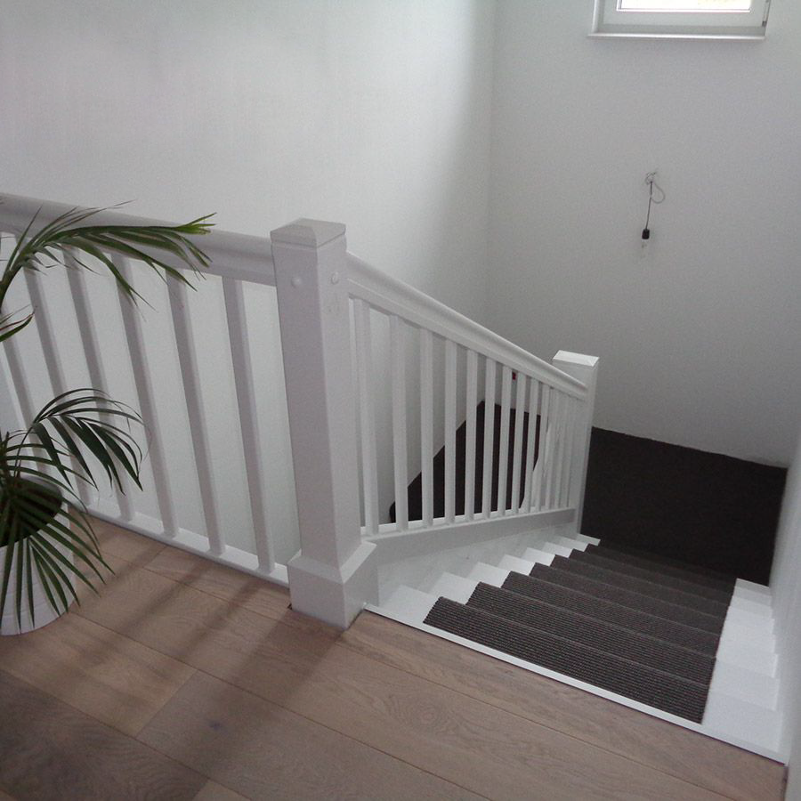 Eine Treppe mit weißem Geländer und braunen Stufen