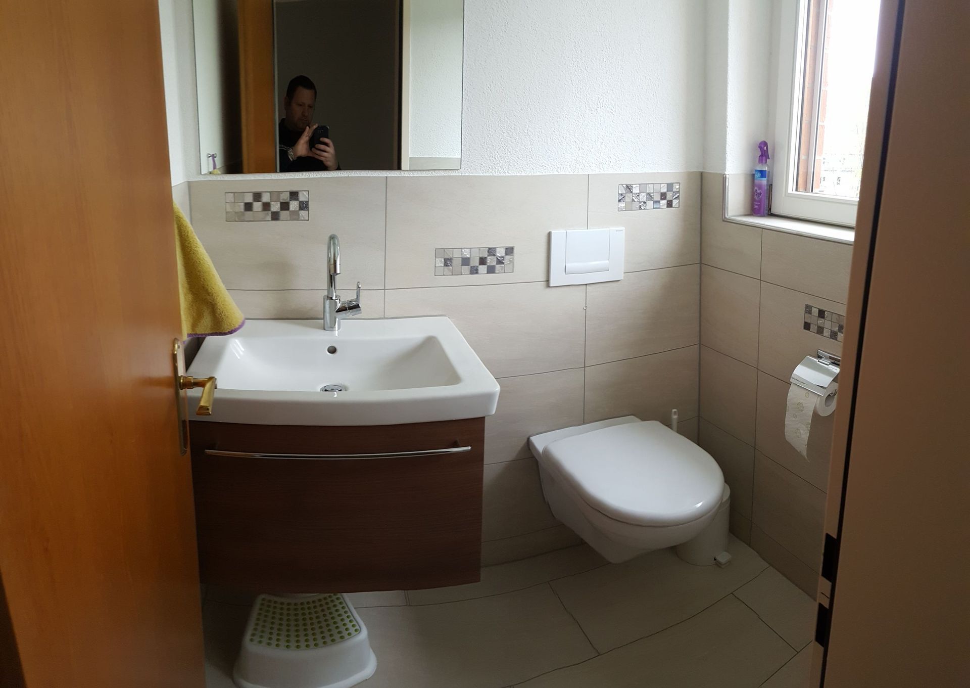 Kleines, modernes Badezimmer mit Waschbecken, Toilette, Spiegel und gefliesten Wänden